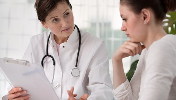 Photo of a female doctor(left) talking to a female patient(right)