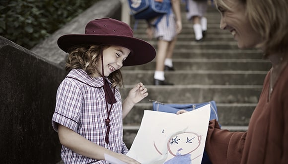 Young child smiling while holding her painting