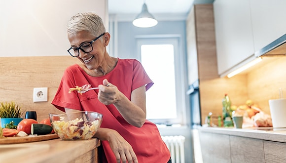 Elderly woman eating at kitchen bench