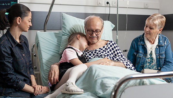 a man in hospital being comforted by a doula and his family