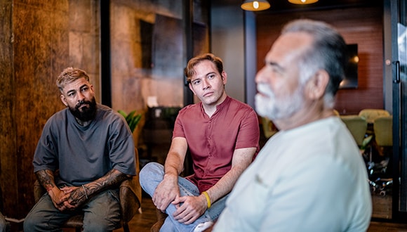 three men talk to each other in a support group