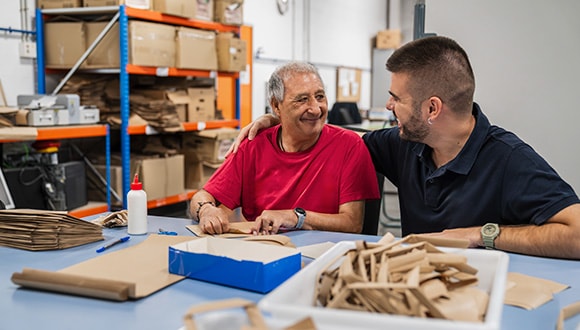 A younger and an older man doing a project together in an act of social connection