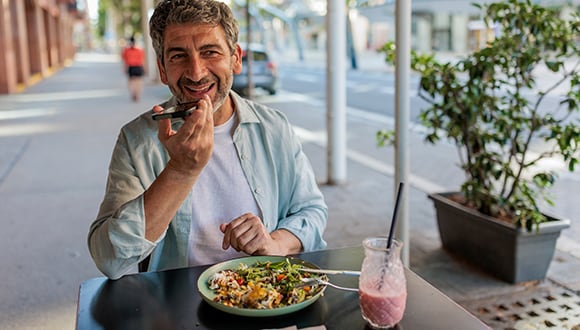 Man sitting outside at a table eating a gut healthy meal