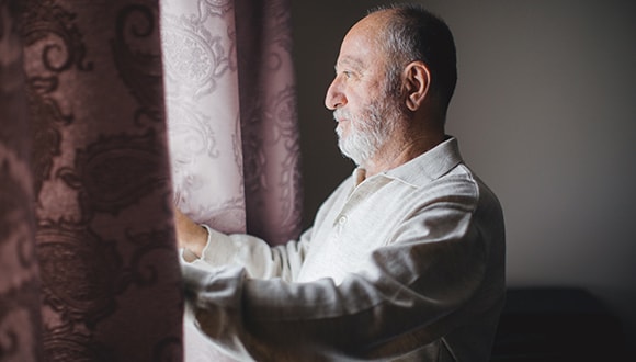 Elderly man looking out the window after a poor night's sleep
