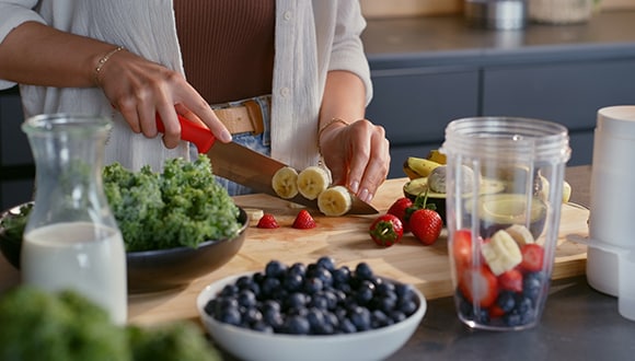 Woman cutting up bananas and other fruit and vegetables