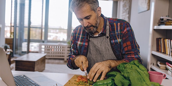 A man cutting vegetables to make a lunch that's not a sandwich