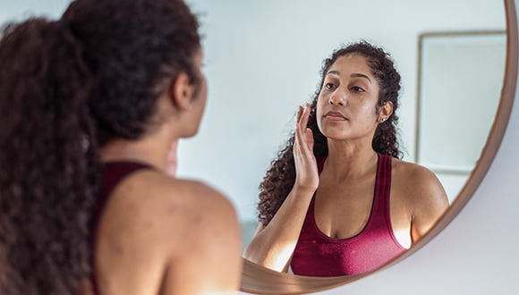 Woman checking skin in mirror