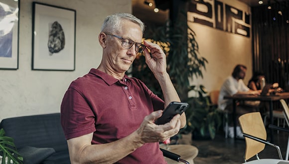 Main wearing glasses looking at phone, straining eyes
