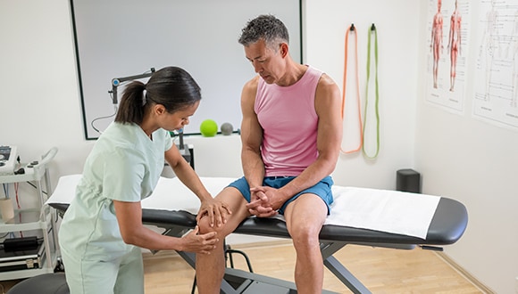 Doctor inspecting a man with knee pain