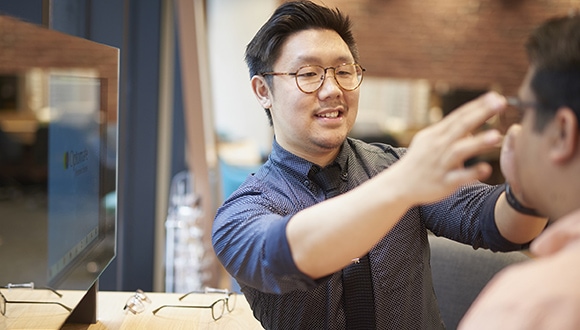 Optometrist putting on new eyeglasses on customer
