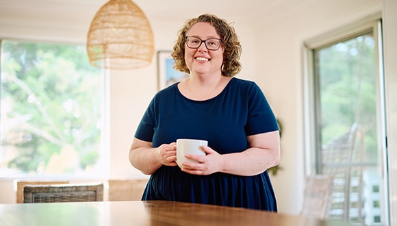 HCF member Jackie stands at a table with a cup of tea