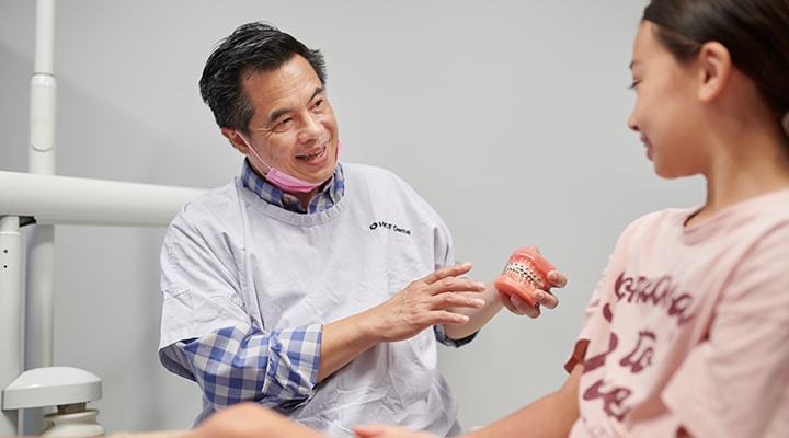 HCF Orthodontist Dr Frank Tan talking to a child about braces
