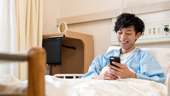 A man in hospital looking at his phone