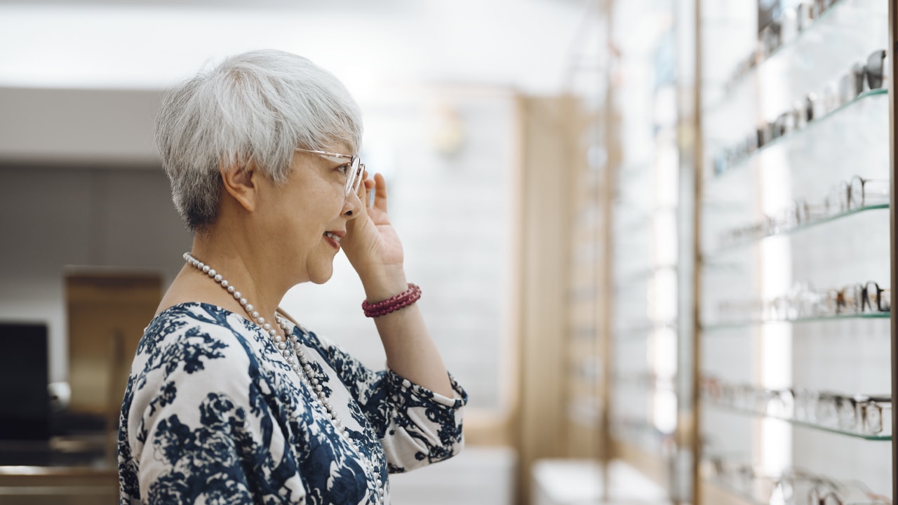 An older woman trying on glasses at an optometrist.