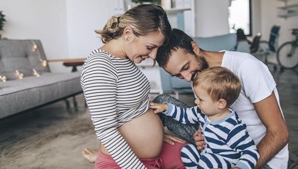 Parents introducing child to new baby, with child touching the mother's belly