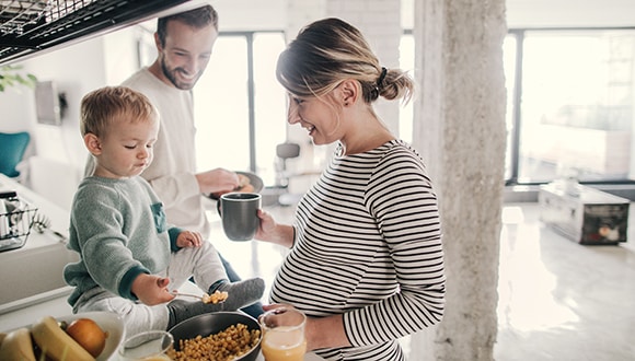 Expectant mother with her son and husband monitoring her pregnancy nutrition while cooking in the kitchen