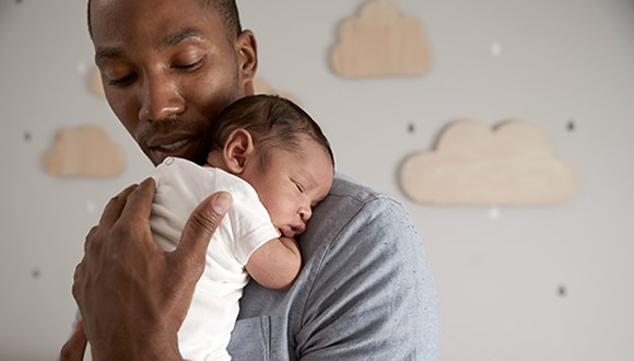 A man being a supportive pregnancy partner while holding his newborn baby