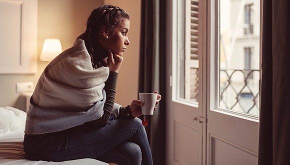 Woman looking contemplatively out of a window after a breakup