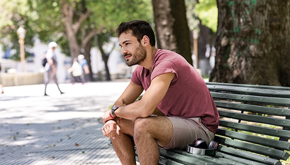 Man sitting on bench looking sad while dealing with his anxiety
