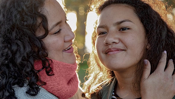 Signs of childhood depression: smiling mother strokes her daughter's hair