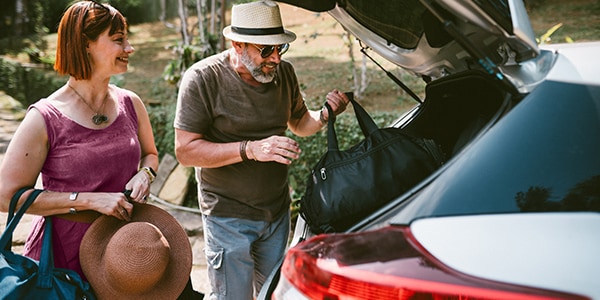 Older couple getting luggage out of a car.