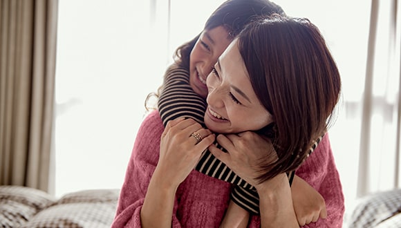 How to help a child with depression: mother laughing with young daughter on her back.