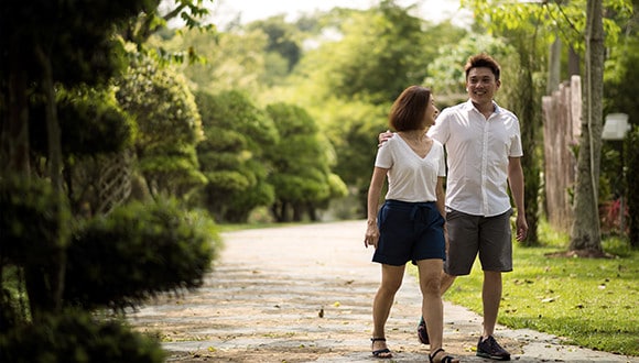 A man and a woman walking through a green park