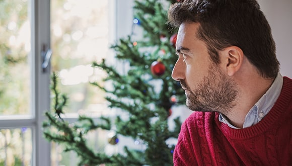 Man looking out a window at Christmas time