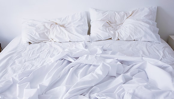Photo of an undone bed with white sheets