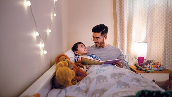 Father and son in bed reading a book before sleep