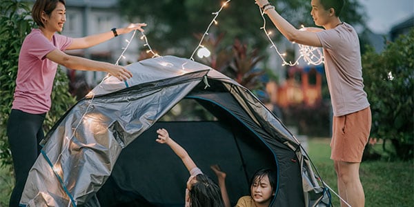 Young people setting up a tent: Camping in your own backyard can be a great way to head outdoors without the convenience.