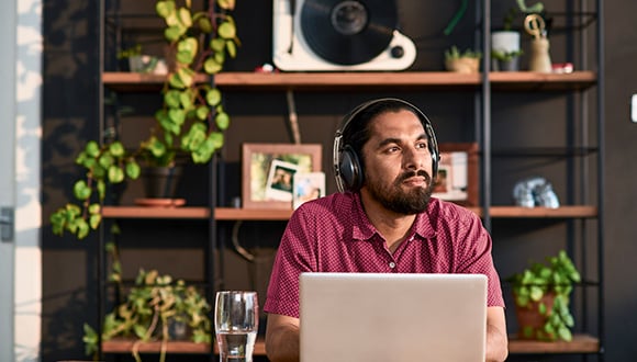 man wearing headphones while on his laptop