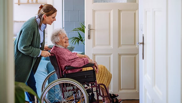 Lady volunteering by pushing elderly lady in a wheelchair