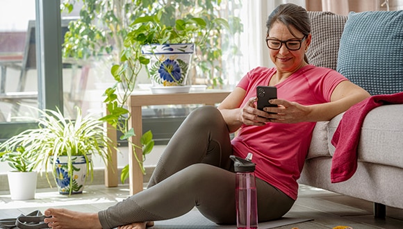 Woman sitting on the yoga mat with her phone