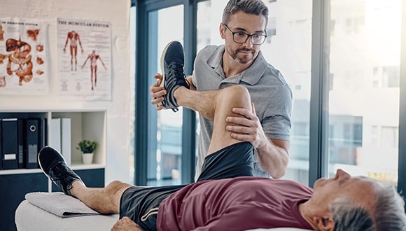 Man getting his knee stretched by a physio