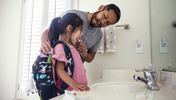 Parent brushing their kids' teeth with an electric toothbrush