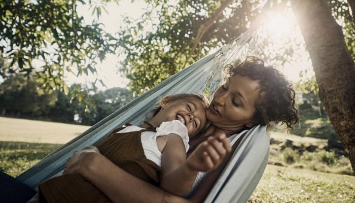 woman with daughter resting on hammock 