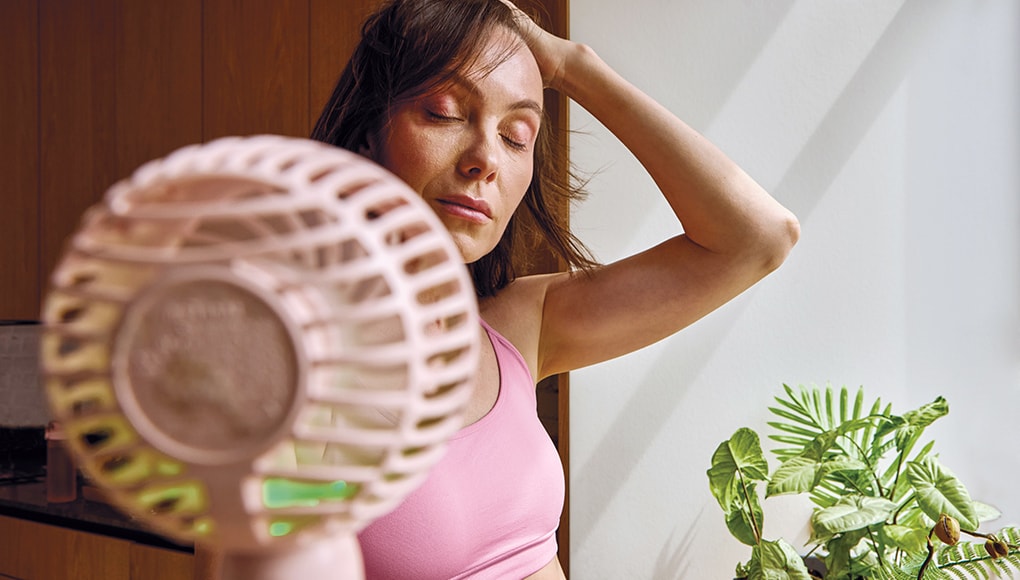 Woman in perimenopause cooling down by a fan