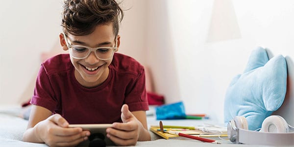 Young boy playing on a mobile phone: It's important to set healthy screen-time boundaries as a family.