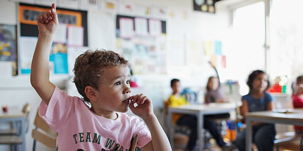 Child putting their hand up in a classroom