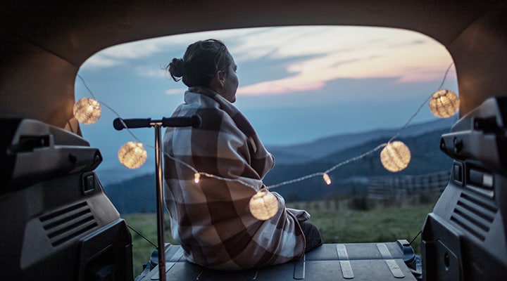 Woman spending time outdoors with blanket wrapped around her.