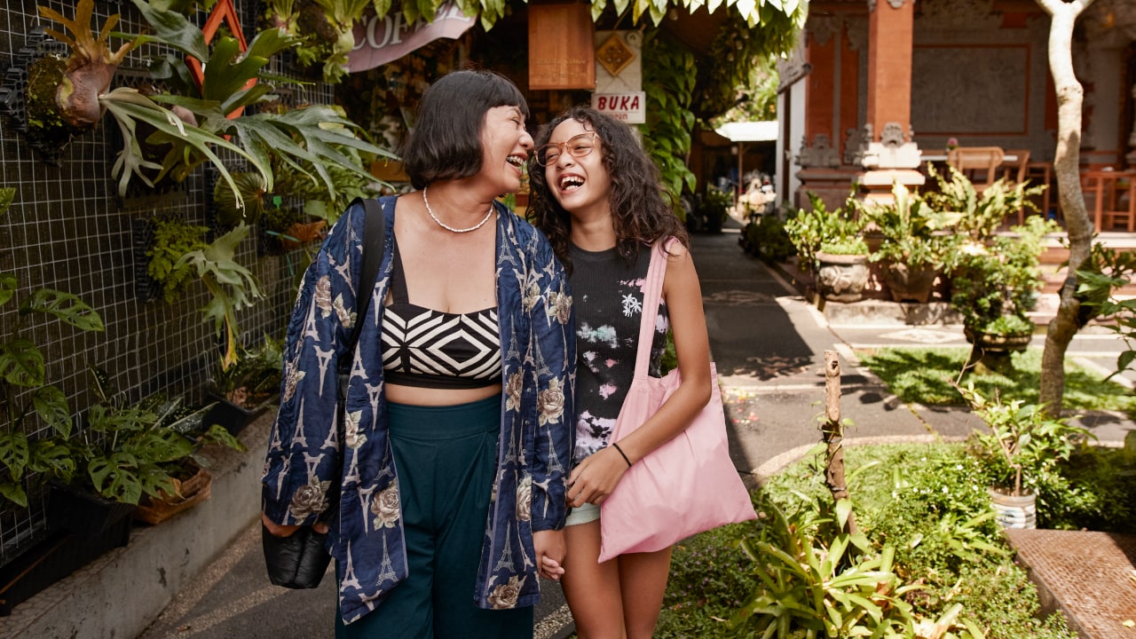 A mother and daughter laughing together while walking on holiday.