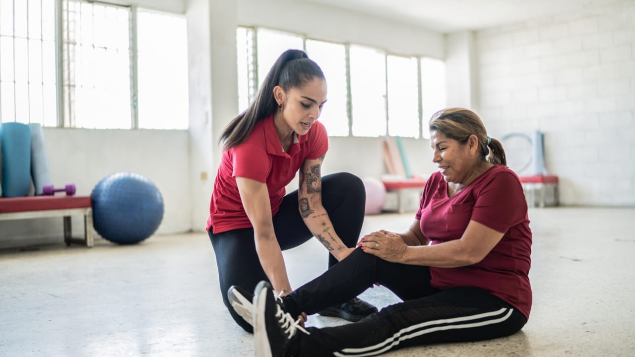 A physiotherapist helps a woman with her exercise program for knee osteoarthritis.