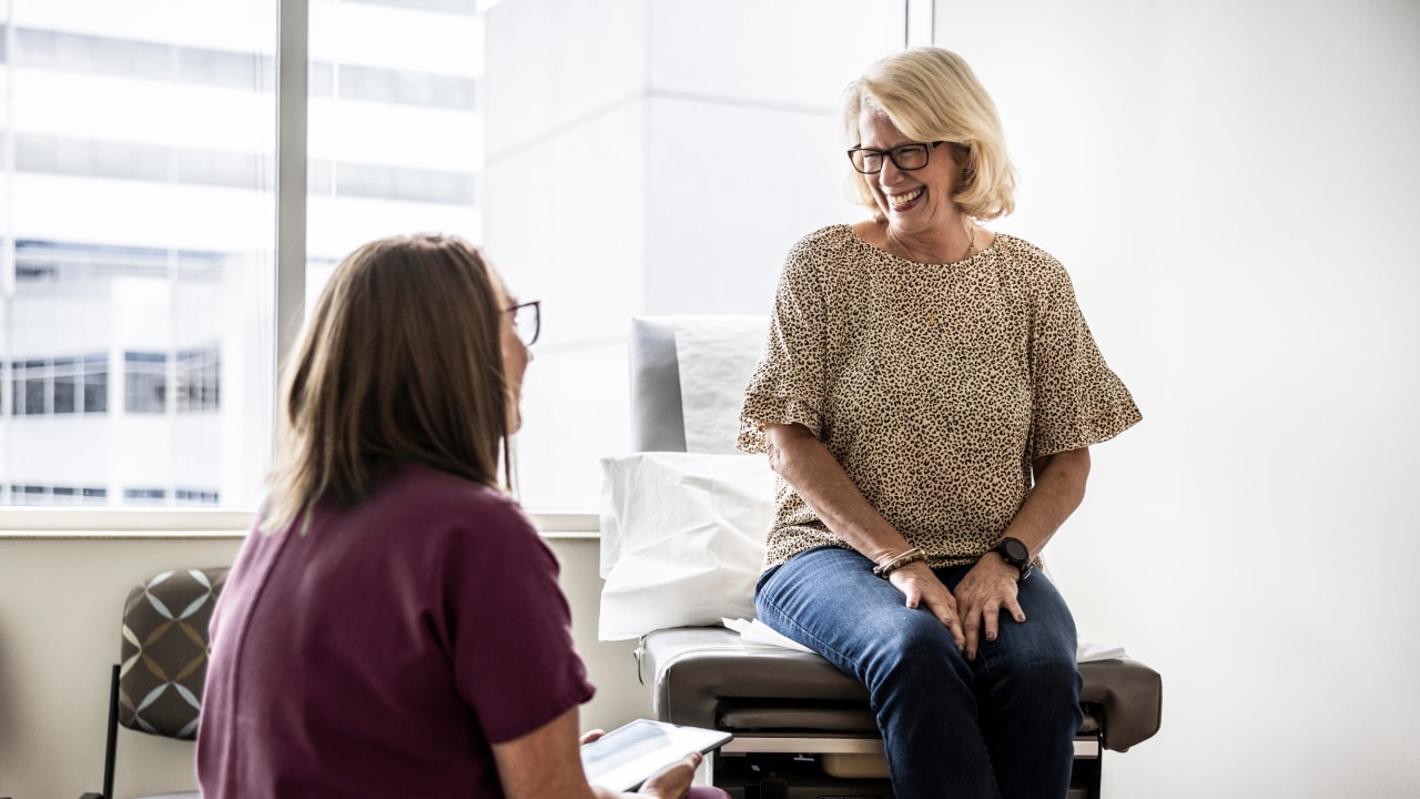 A woman sitting on a doctor bed during a consultation.
