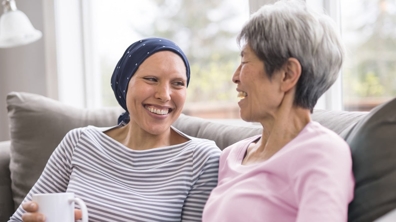 A lady battling cancer smiles with her supportive friend.