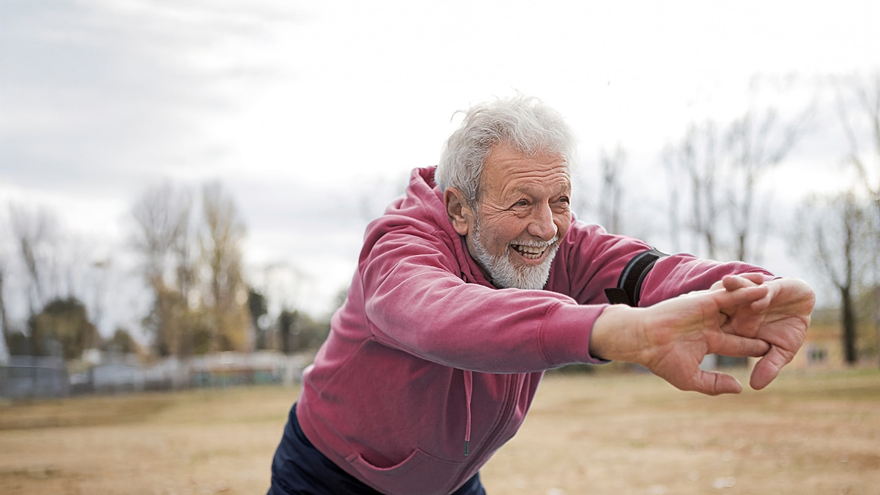 A man stretching his arms while exercising outside.