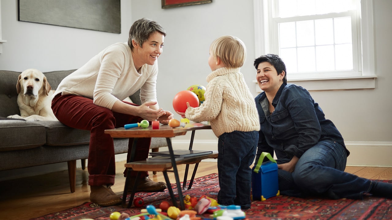 A family sitting in the lounge room playing with a ball.