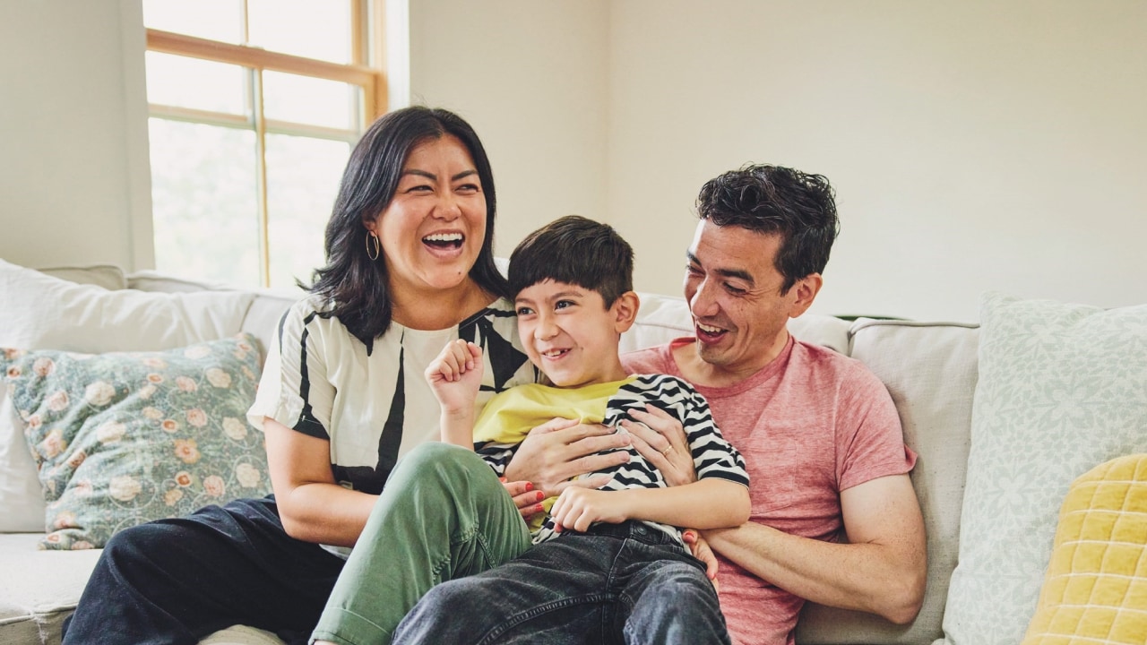 Mother, father and son laughing on the lounge.