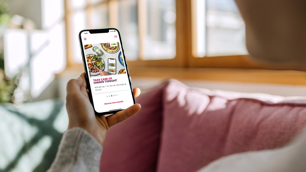 Person sitting on the couch looking at the HCF Thank You app on their mobile.