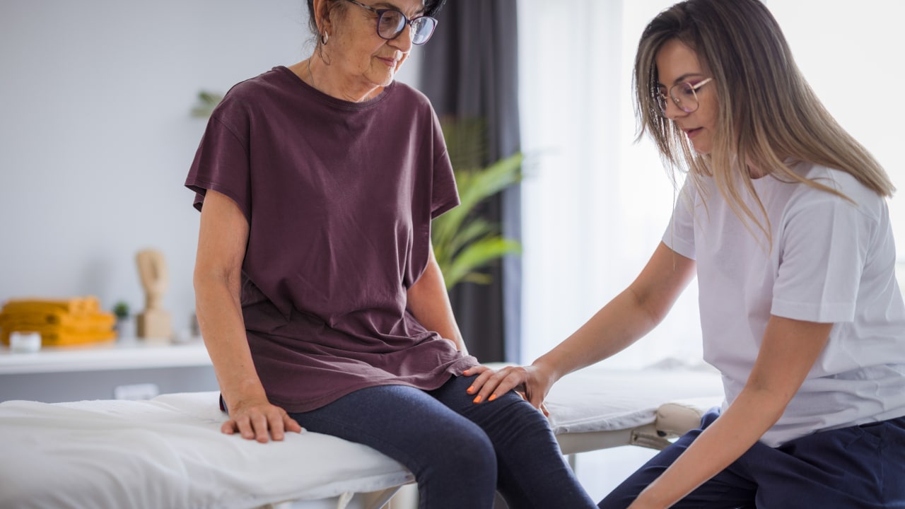 A woman having her knee assessed by a doctor.
